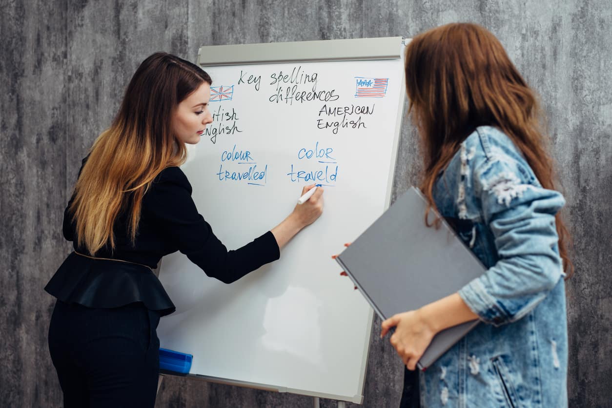 Mujeres apuntando en pizarra las diferencias entre inglés britanico y americano